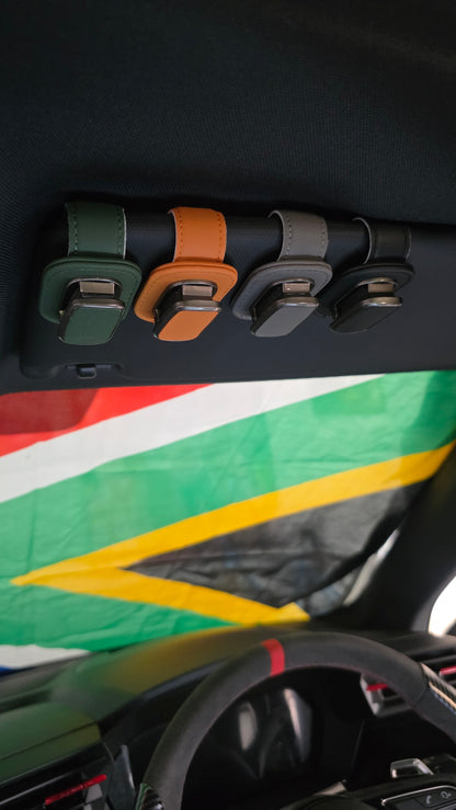 The Car Edit Visor Clip in green, tan, grey and black clipped to a car sun visor