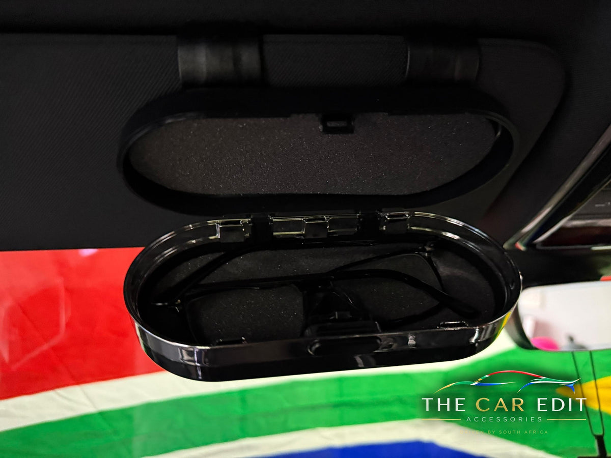 The Chrome Case open on a car sun visor showing sunglasses in the soft-lined interior