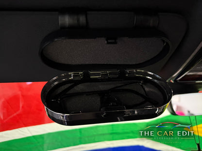 The Chrome Case open on a car sun visor showing sunglasses in the soft-lined interior